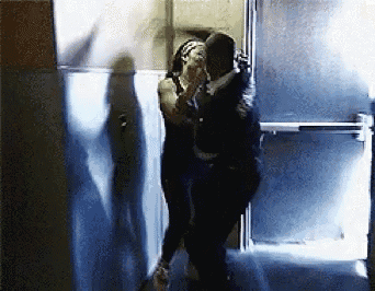 a man and woman are hugging in a hallway .