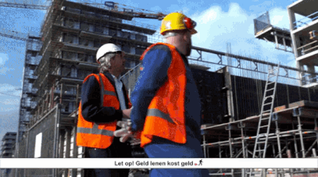 two construction workers wearing orange vests and hard hats are standing in front of a building that says let op