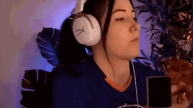 a woman wearing headphones is sitting in front of a microphone and holding a cell phone .