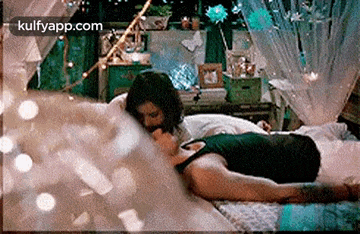 a man and a woman are kissing on a bed in a room .