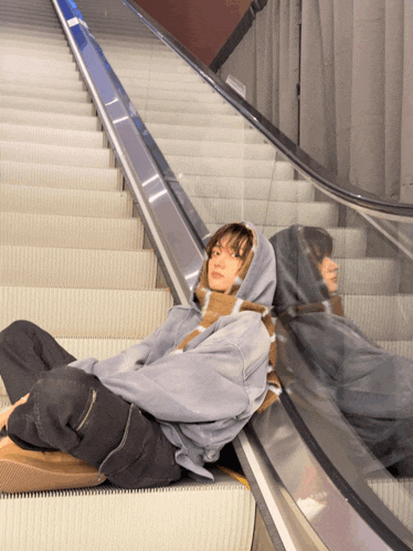 a person sitting on an escalator with a hoodie on