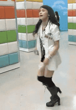 a woman in a white coat and black boots dancing