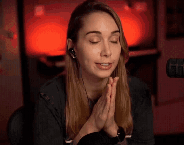 a woman with her eyes closed and her hands folded praying