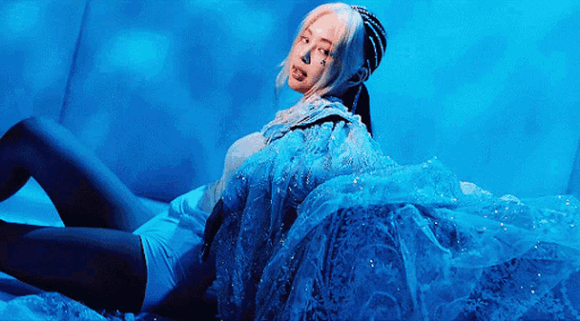 a woman in a blue dress laying on a bed