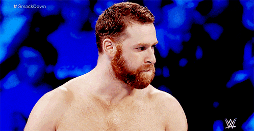 a shirtless man with a beard stands in front of a blue background with the letters w on it
