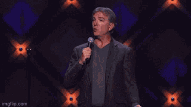 a man in a suit is standing on a stage holding a microphone