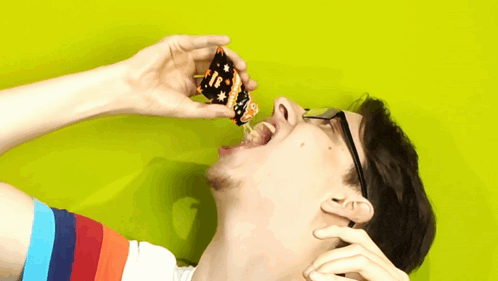 a man with glasses is eating a piece of candy that says ' i love you '