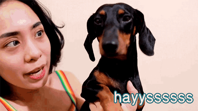 a woman holding a dachshund with hayyssss written in blue letters