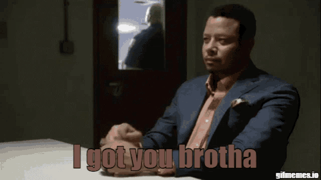 a man sitting at a table with the words " i got you brotha " on the screen