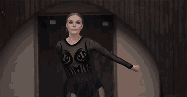 a woman in a black bodysuit is dancing in front of a door .