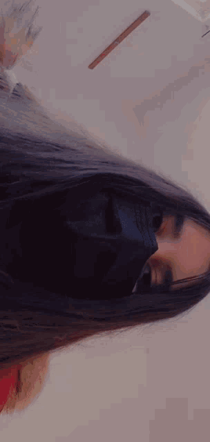 a woman wearing a black face mask is making a heart shape with her hand