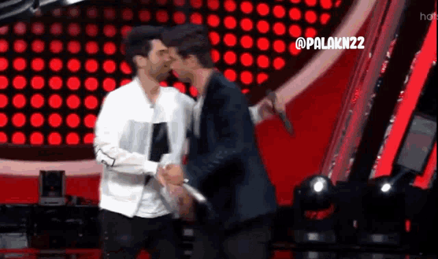 two men are standing next to each other on a stage and one has a microphone .