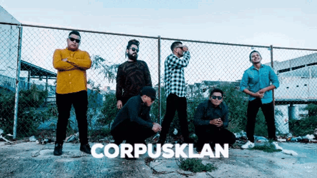 a group of men are posing in front of a chain link fence and the word corpusklan is on the ground