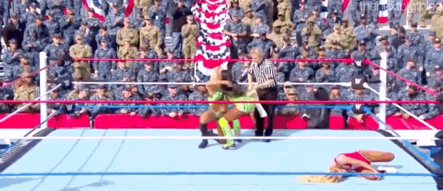 two women are wrestling in a ring in front of a crowd of soldiers