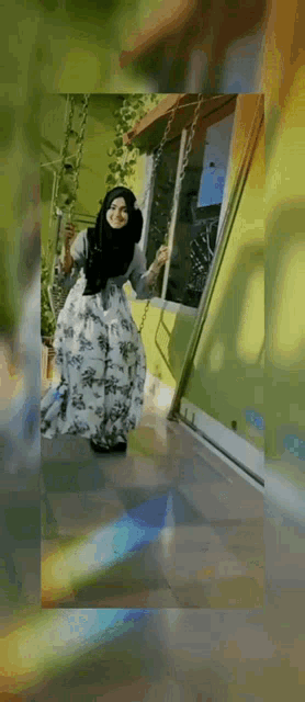 a woman in a hijab is swinging on a swing outside of a building .
