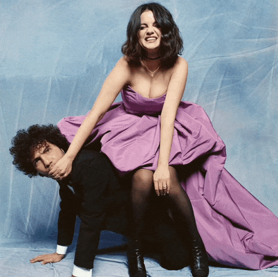 a woman in a purple dress sits on the back of a man