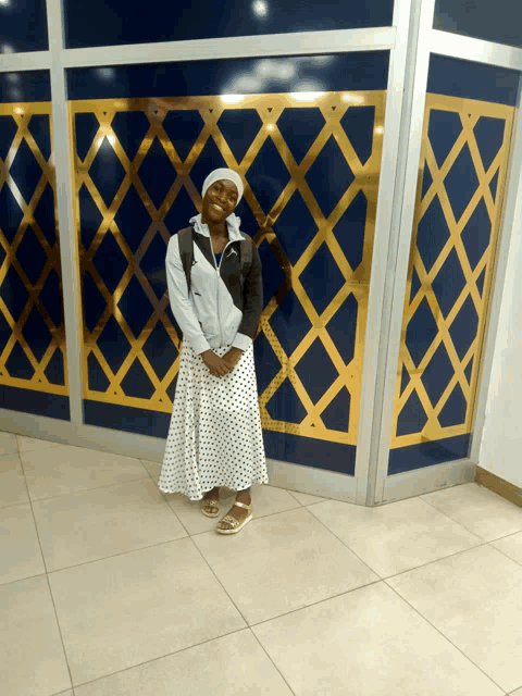 a woman in a polka dot skirt stands in front of a wall