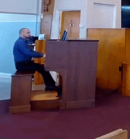 a man in a blue shirt is playing a piano