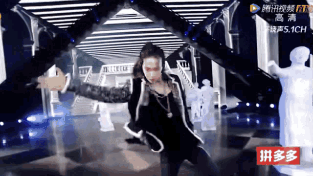 a man in a black jacket is dancing on a stage with a sign that says ' 拼 多 多 ' on it
