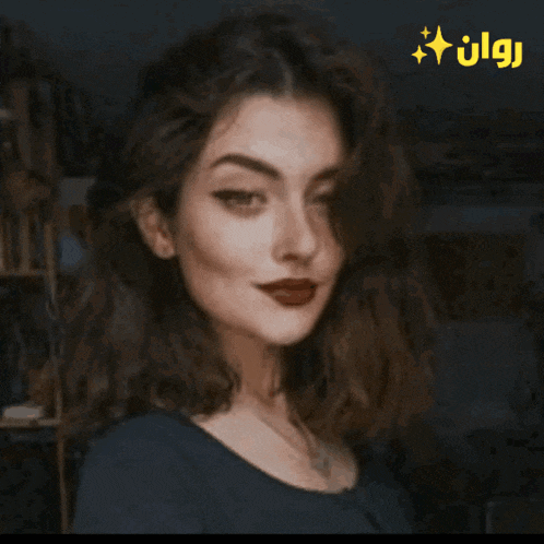 a woman with dark hair and red lips looks at the camera with a yellow star above her