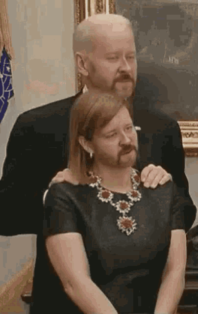 a man with a beard is standing next to a woman with a necklace .