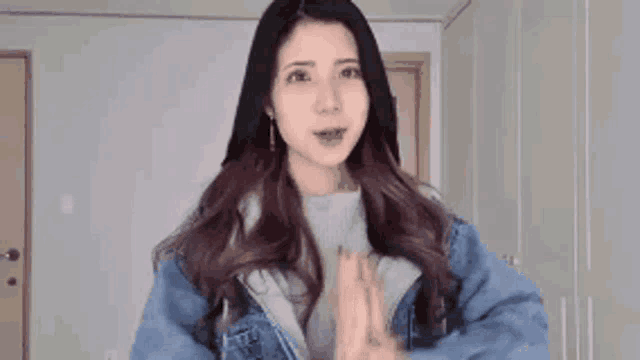 a woman in a blue denim jacket is standing in a room .