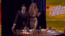 a man and a woman are standing at a table in front of a sign that says casa famoso .