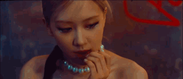 a woman wearing a pearl necklace covering her mouth with her hand