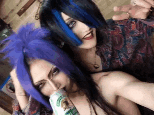 a woman with purple hair and a man with blue hair pose for a picture
