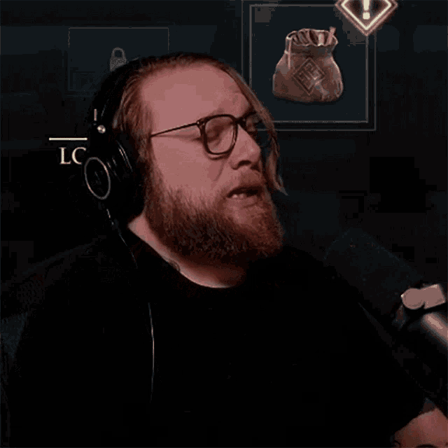 a man wearing headphones and glasses is talking into a microphone with a bag in the background that says lc on it
