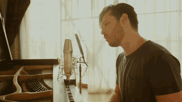 a man in a black shirt is playing a piano