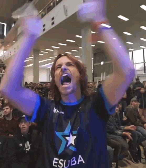 a man wearing a shirt that says esuba is screaming with his arms in the air