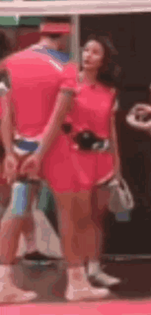 a woman in a pink dress is standing next to a man in a red shirt .