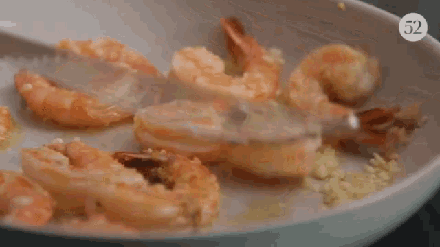a pan of shrimp is being stirred with a fork with the number 52 on the bottom