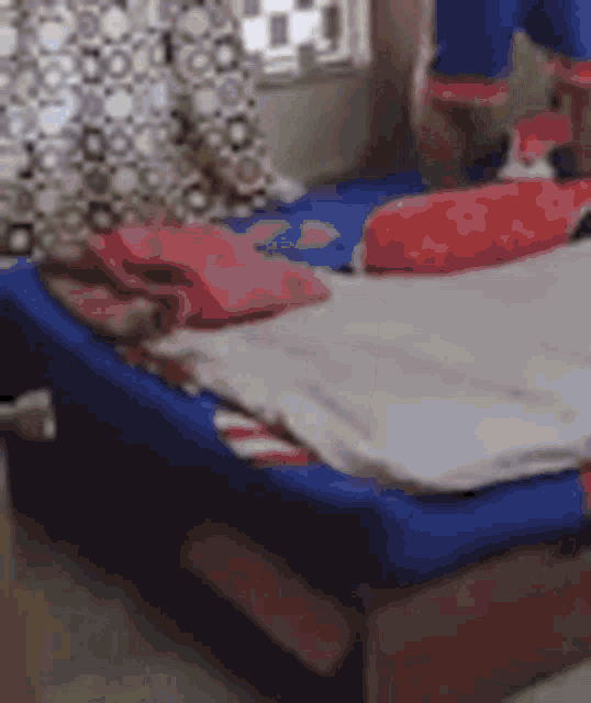 a person is standing on a bed in a bedroom with a blue mattress .