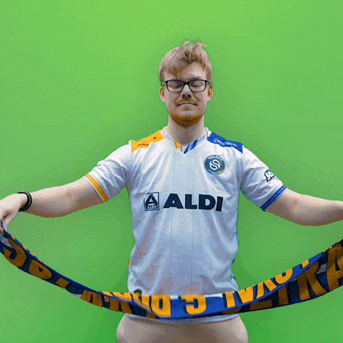 a man wearing an aldi shirt holds a scarf