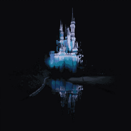 a castle is lit up with blue lights and is reflected in the water