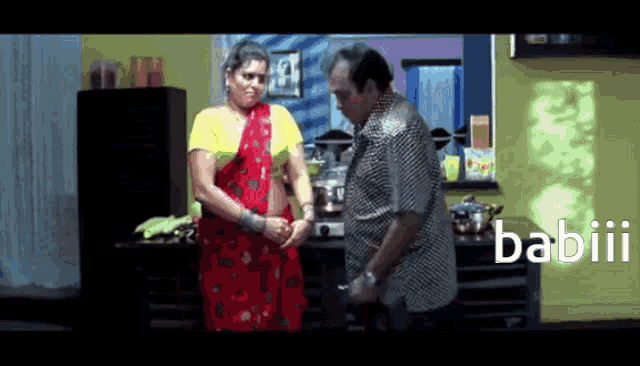 a man and a woman are standing in a kitchen with the word babiii on the bottom right