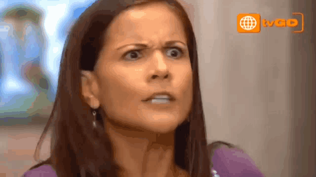 a woman in a purple shirt is making a funny face in front of a sign that says wao