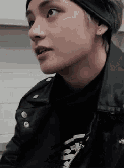 a close up of a person 's face wearing a leather jacket and a headband .