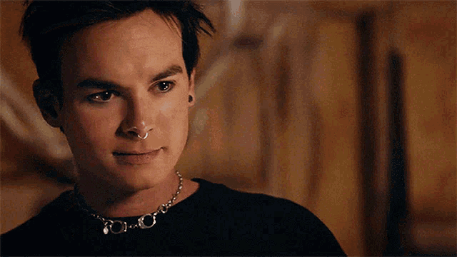 a young man with a nose ring and a chain around his neck