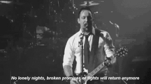 a man is playing a guitar and singing into a microphone on stage .