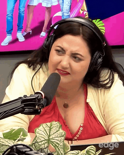 a woman wearing headphones is sitting in front of a microphone with the word edge on the bottom right