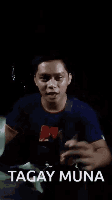 a man in a blue shirt is holding a cup in his hand and making a funny face .