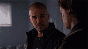 two men are standing next to each other in a dark room and talking .