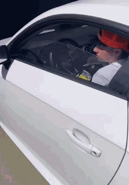 a man in a hard hat is driving a white audi