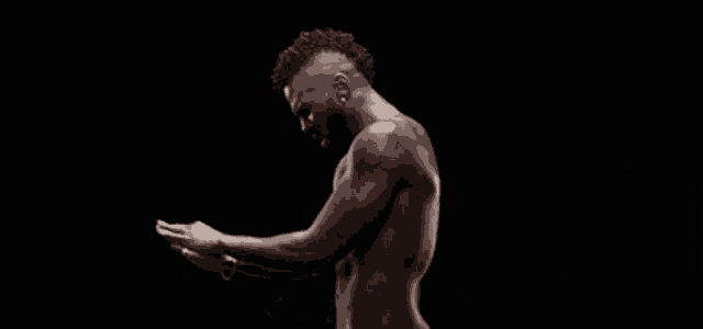 a man without a shirt is looking at his phone in the dark