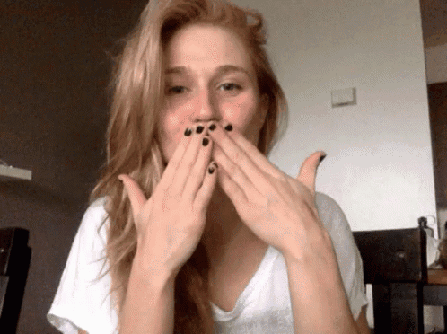 a woman covering her mouth with her hands and has black nails