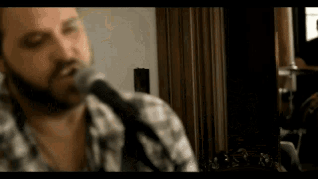 a man with a beard singing into a microphone with his eyes closed