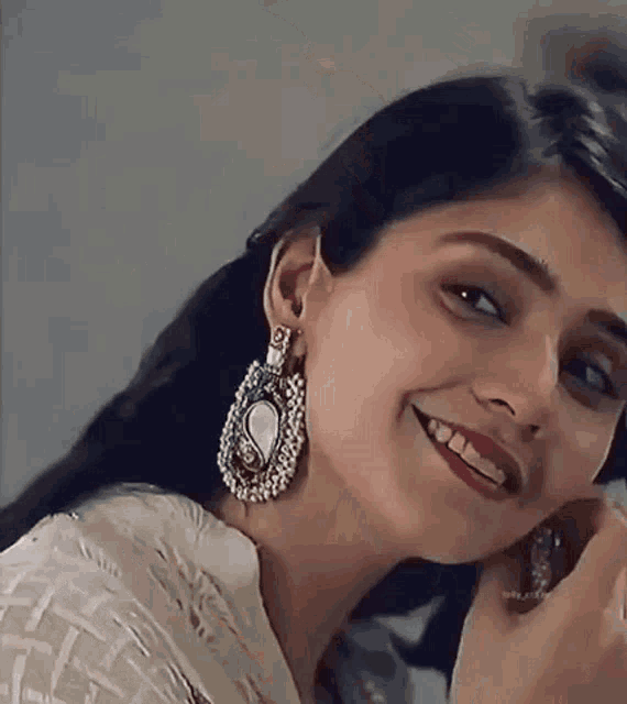a close up of a woman wearing earrings and a ring .